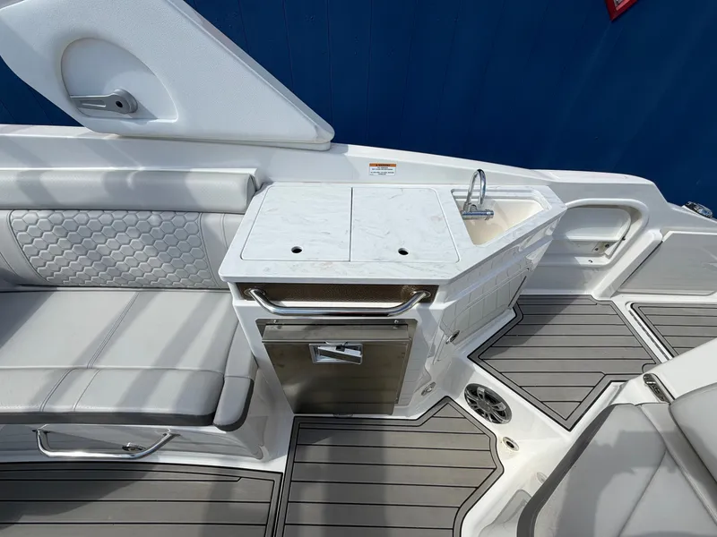 Slide: The Image of The 2025 Sea Ray SDX 290 features an elegant seating area with gray upholstery and a small sink. - 18