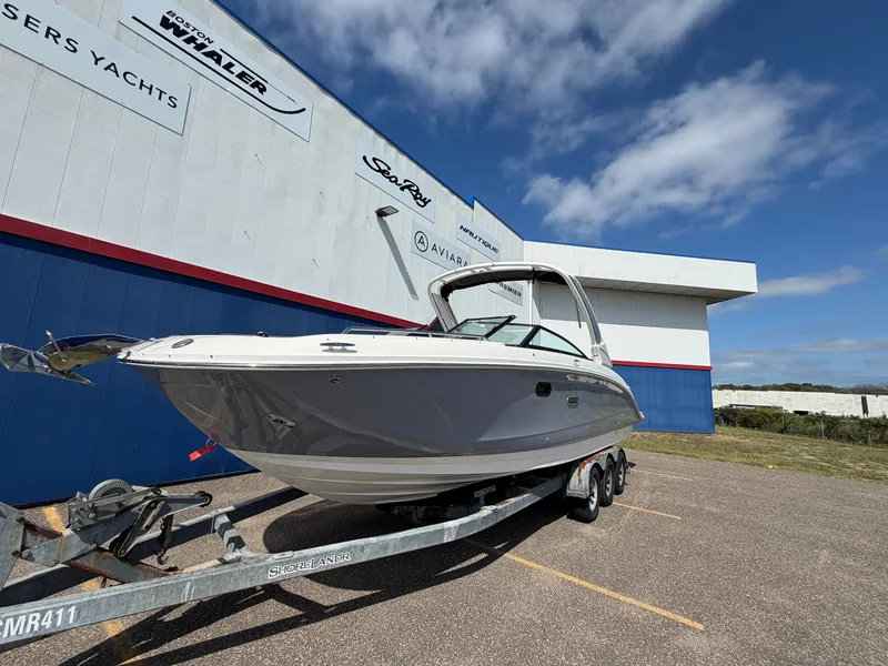 Slide: The Image of A 2025 Sea Ray SDX 290 on a trailer in front of a building with boat company logos. - 4