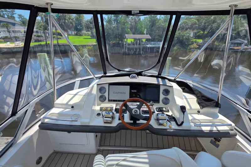 Slide: The Image of Helm of 2007 Sea Ray 36 Sedan Bridge with Garmin navigation system, docked by a serene waterfront. - 16