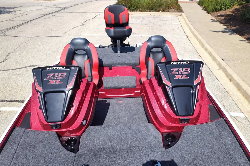 Slide: The Image of 2027 Nitro Z18 XL Pro boat with red and black seating in a parking lot. - 13