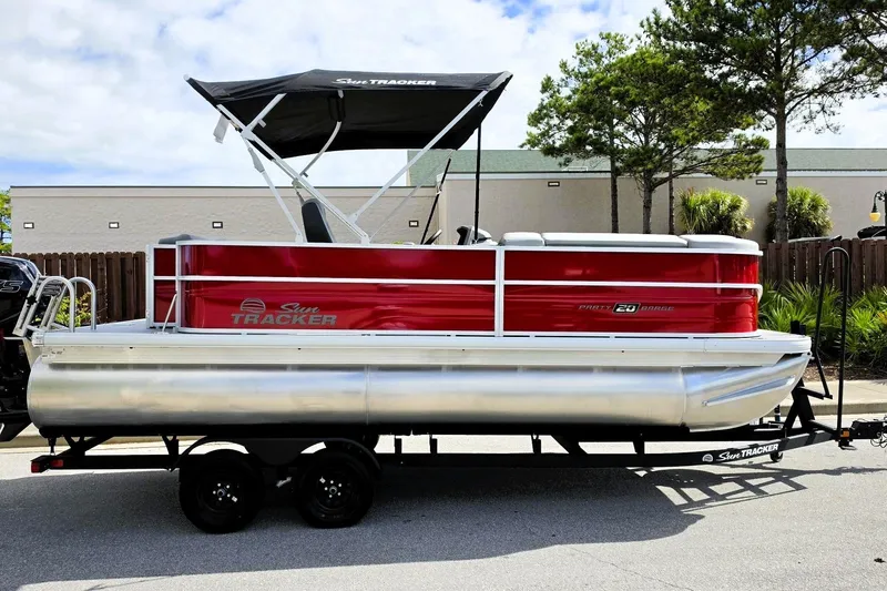 The Image of 2027 Sun Tracker Party Barge 20 DLX pontoon boat on trailer, red and silver design. - 0