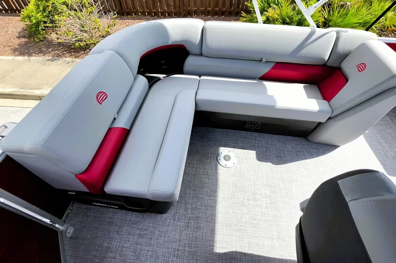 Slide: The Image of 2027 Sun Tracker Party Barge 20 DLX with gray and red seating, outdoor setting. - 18