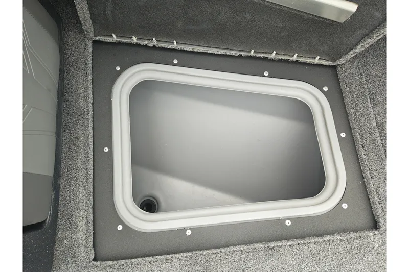 Slide: The Image of 2026 Tracker Targa V-19 WT boat storage compartment with gray interior and carpeted edges. - 30
