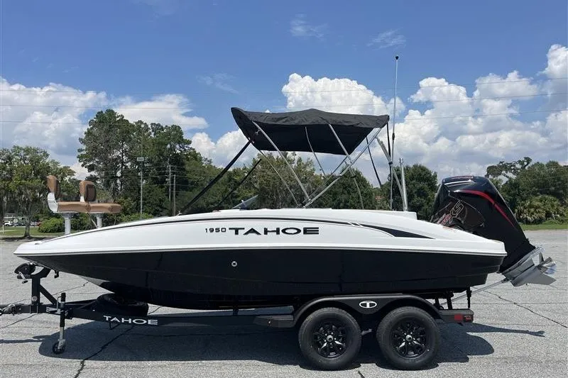 The Image of 2026 Tahoe 1950 boat on trailer, black and white design, under clear blue sky. - 0