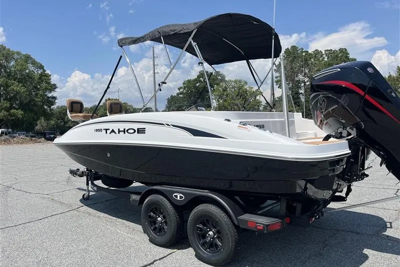 Slide: The Image of 2026 Tahoe 1950 boat on trailer with canopy, parked outdoors under blue sky. - 3