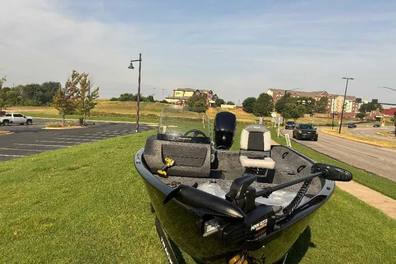 Slide: The Image of 2027 Tracker Pro Guide V-16 SC boat on grassy area near parking lot and road. - 19