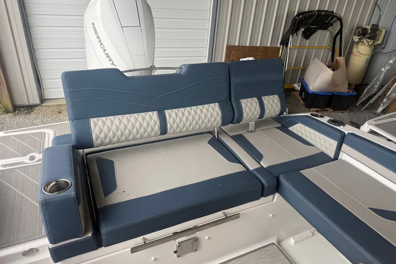Slide: The Image of 2025 Monterey Elite 27 OB boat interior with blue and white seating, cup holders, and Mercury engine. - 8
