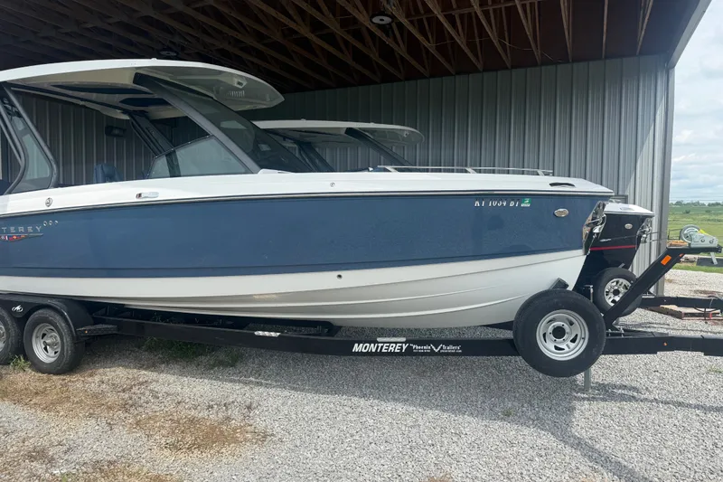 Slide: The Image of 2025 Monterey Elite 27 OB boat on trailer, parked in a covered area. - 2