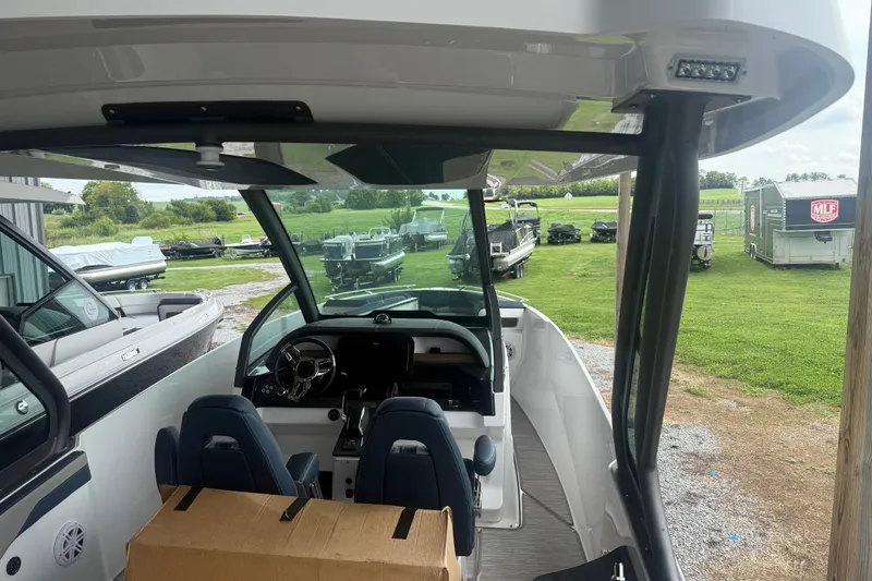 Slide: The Image of 2025 Monterey Elite 27 OB boat interior with steering wheel and seating, parked outdoors. - 7