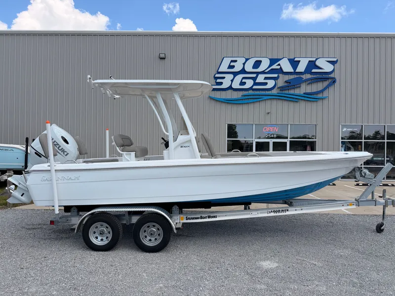 The Image of The image shows a 2027 Savannah 210X boat on a trailer in front of a boat building. - 0