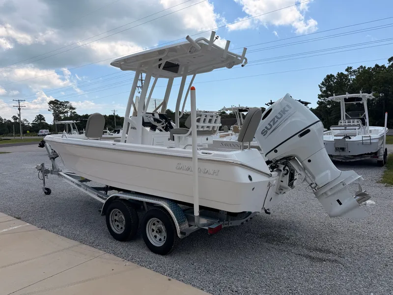 Slide: The Image of A white Savannah 210X boat on a trailer, featuring a Suzuki outboard motor. - 3