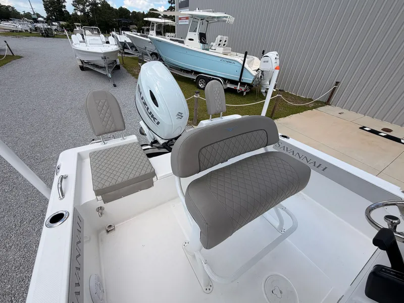 Slide: The Image of The image shows the cockpit of a 2027 Savannah 210X boat with gray upholstery and an outboard motor. - 13
