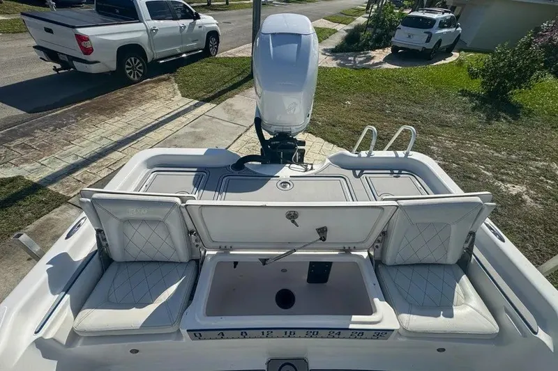 Slide: The Image of 2018 Blue Wave 2400 PureBay boat with open storage compartments and motor, parked on driveway. - 52