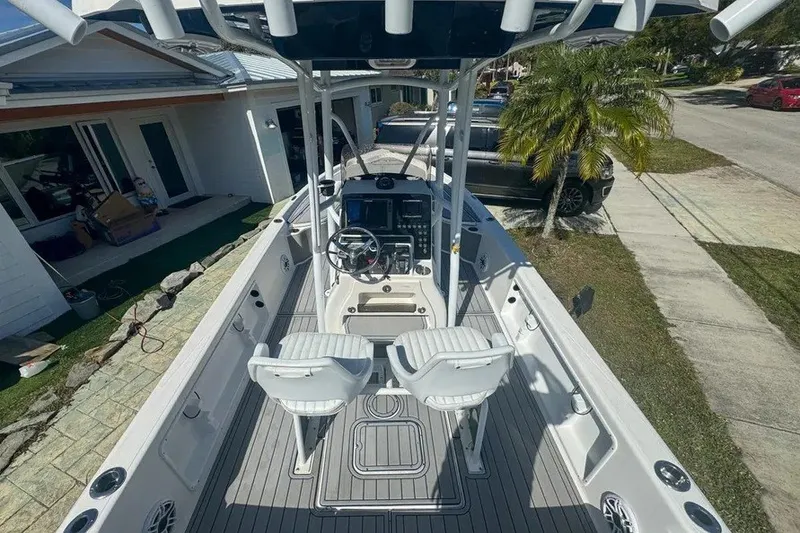 Slide: The Image of 2018 Blue Wave 2400 PureBay boat with dual seats and steering console, parked in driveway. - 16
