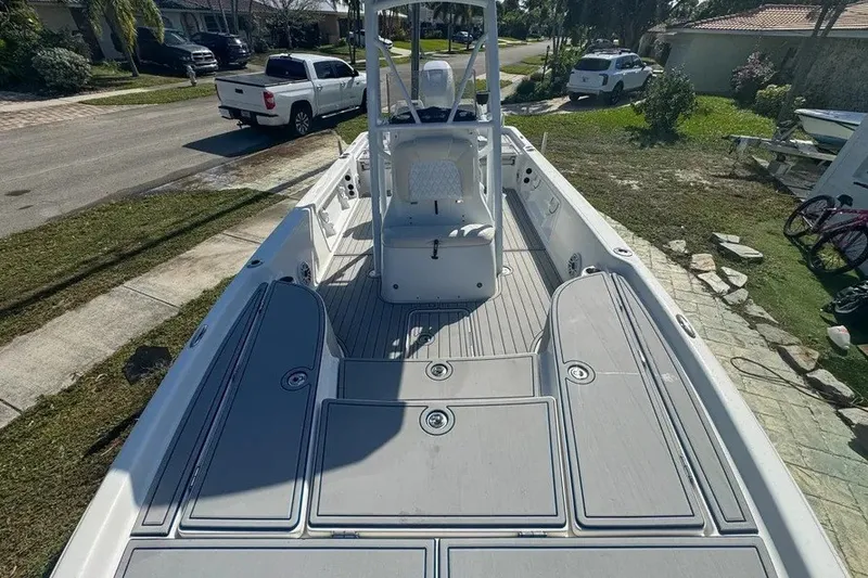 Slide: The Image of 2018 Blue Wave 2400 PureBay boat with spacious deck and seating, parked in a residential area. - 32