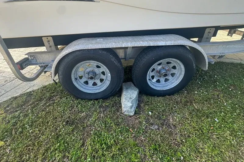 Slide: The Image of Trailer wheels of a 2018 Blue Wave 2400 PureBay boat, secured with a rock. - 74