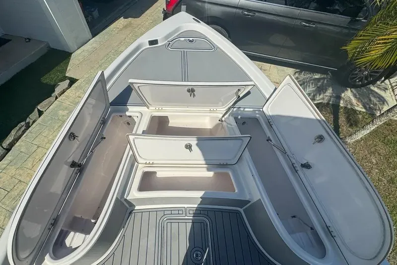 Slide: The Image of 2018 Blue Wave 2400 PureBay boat with open storage compartments, parked on a driveway. - 27