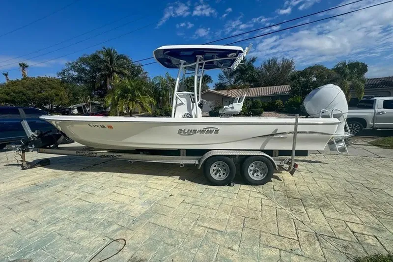 The Image of 2018 Blue Wave 2400 PureBay boat on trailer, parked in driveway under clear sky. - 1
