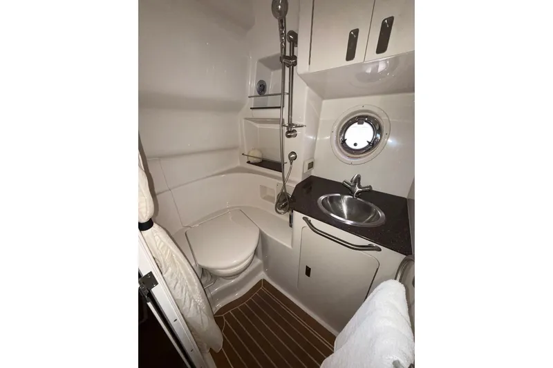 Slide: The Image of 2012 Sea Ray 335 Sundancer bathroom with sink, toilet, and porthole window. - 22