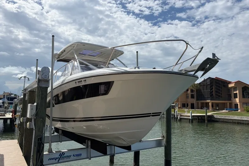 The Image of 2019 Jeanneau Leader 9.0 WA boat on lift at marina, under cloudy sky. - 0