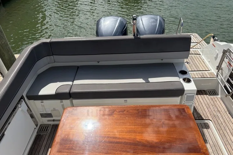 Slide: The Image of 2019 Jeanneau Leader 9.0 WA boat with cushioned seating and wooden table on deck. - 6
