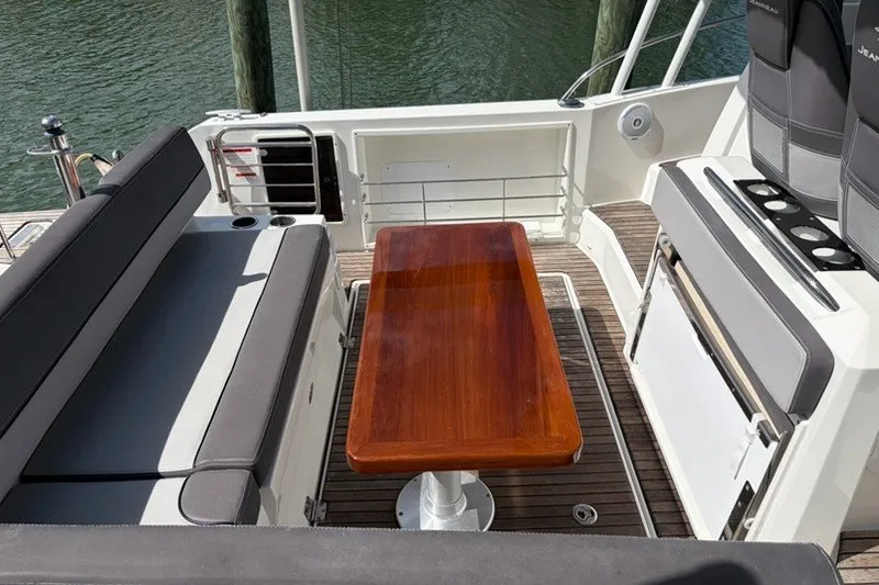 Slide: The Image of 2019 Jeanneau Leader 9.0 WA boat interior with wooden table and cushioned seating. - 5