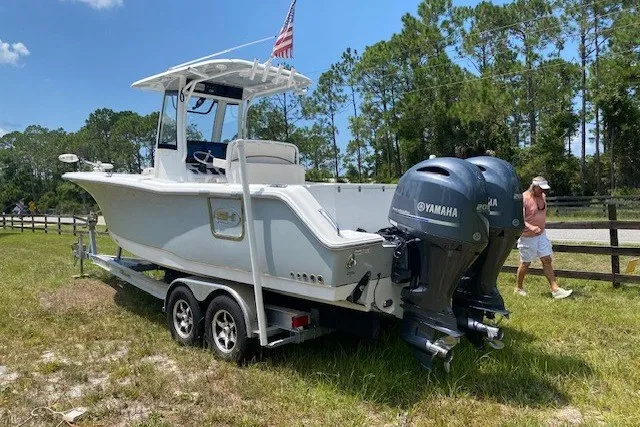 Slide: The Image of 2022 Sea Hunt Gamefish 27CB boat with dual Yamaha engines on a trailer. - 24
