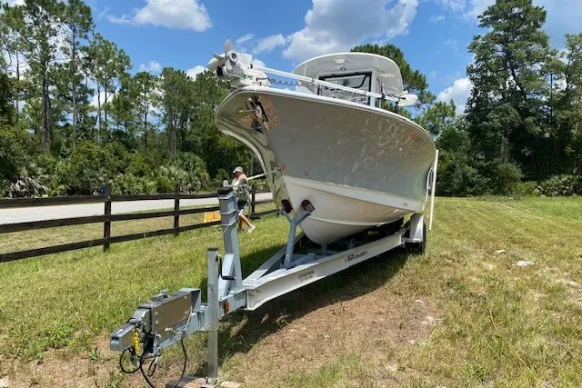 Slide: The Image of 2022 Sea Hunt Gamefish 27CB boat on trailer, parked on grassy area with trees. - 25
