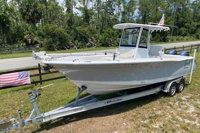 Slide: The Image of 2022 Sea Hunt Gamefish 27CB boat on trailer, parked outdoors near trees. - 29