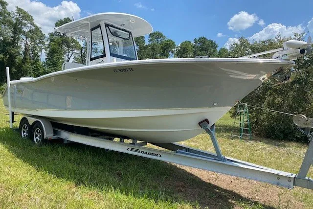 Slide: The Image of 2022 Sea Hunt Gamefish 27CB boat on trailer in grassy area, under blue sky. - 28