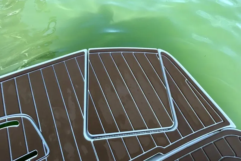 Slide: The Image of 2007 Sea Ray 260 Sundeck swim platform with brown decking, near green water. - 26
