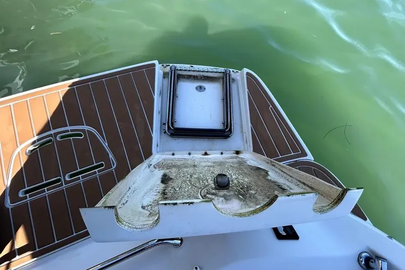Slide: The Image of 2007 Sea Ray 260 Sundeck boat deck with storage compartment, near green water. - 27
