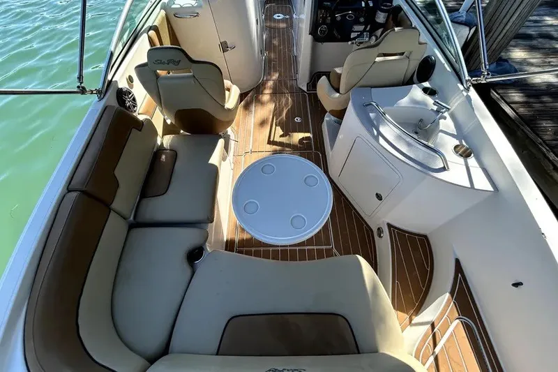 Slide: The Image of 2007 Sea Ray 260 Sundeck interior with seating, table, and helm, docked on calm water. - 22