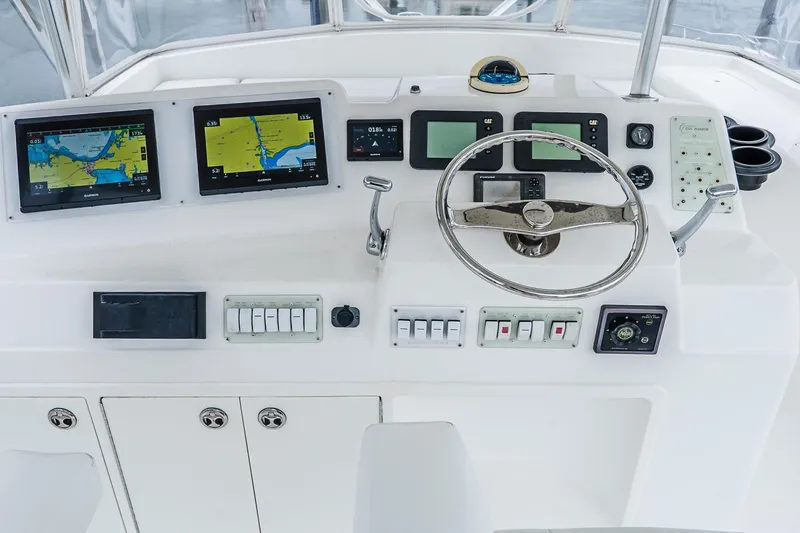 Slide: The Image of Control panel of a 2003 Egg Harbor 42 Convertible yacht with navigation screens and steering wheel. - 32