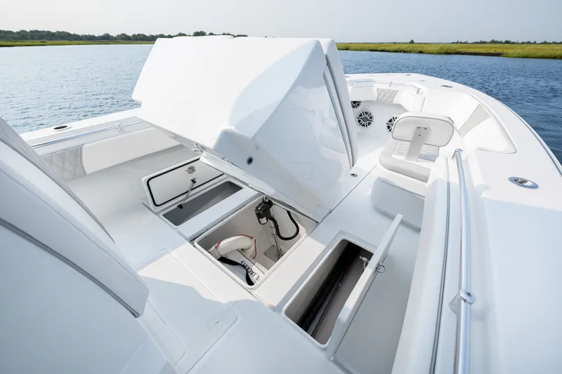 Slide: The Image of 2025 Contender 32 ST boat with open storage compartments on a calm waterway. - 19