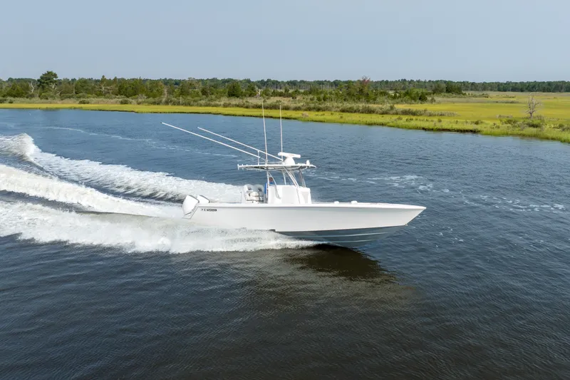 Slide: The Image of 2025 Contender 32 ST boat cruising on a serene river with lush green banks. - 5