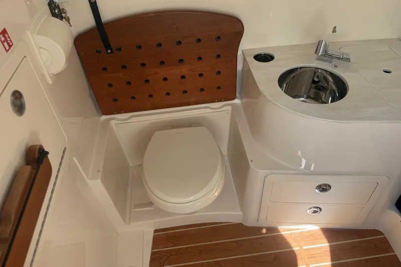 Slide: The Image of 2026 Grady-White Canyon 336 boat bathroom with toilet, sink, and wooden accents. - 25