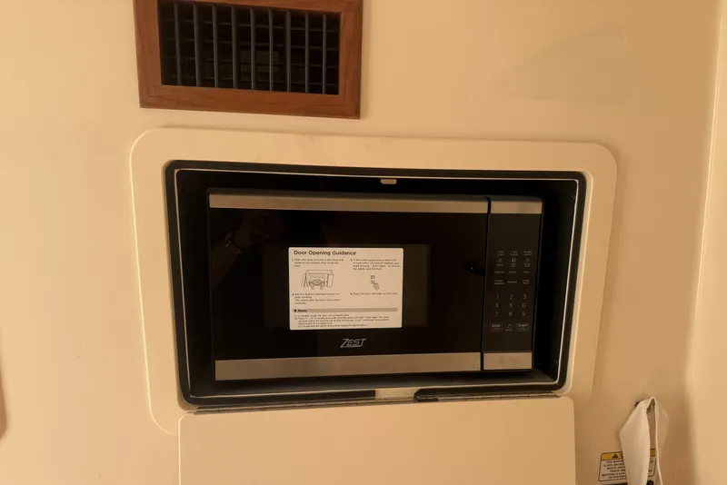Slide: The Image of Built-in microwave on 2026 Grady-White Canyon 336 boat, featuring digital controls and door opening guidance. - 28