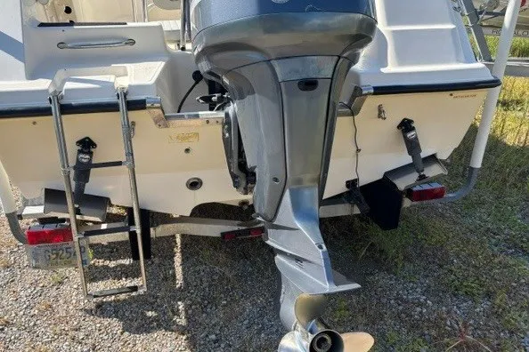 Slide: The Image of 2005 Key West 225 Center Console boat with outboard motor and ladder, parked on gravel. - 6