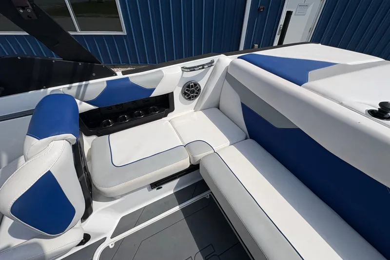 Slide: The Image of 2021 Axis A20 boat interior with blue and white seating, cup holders, and speaker. - 13