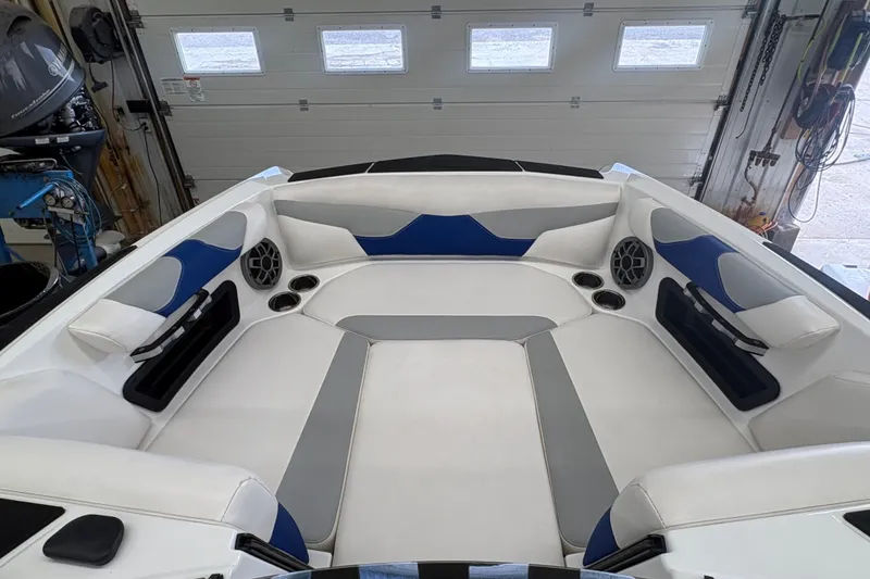 Slide: The Image of 2021 Axis A20 boat interior with white, blue, and gray seating in a garage setting. - 27
