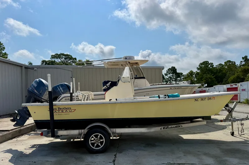 The Image of 2012 Jones Brothers Bateau 20 boat on trailer, parked outdoors under a partly cloudy sky. - 1
