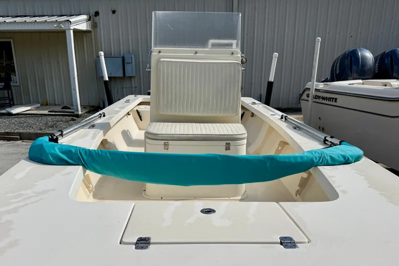 Slide: The Image of 2012 Jones Brothers Bateau 20 boat with teal cover, docked near a building. - 4