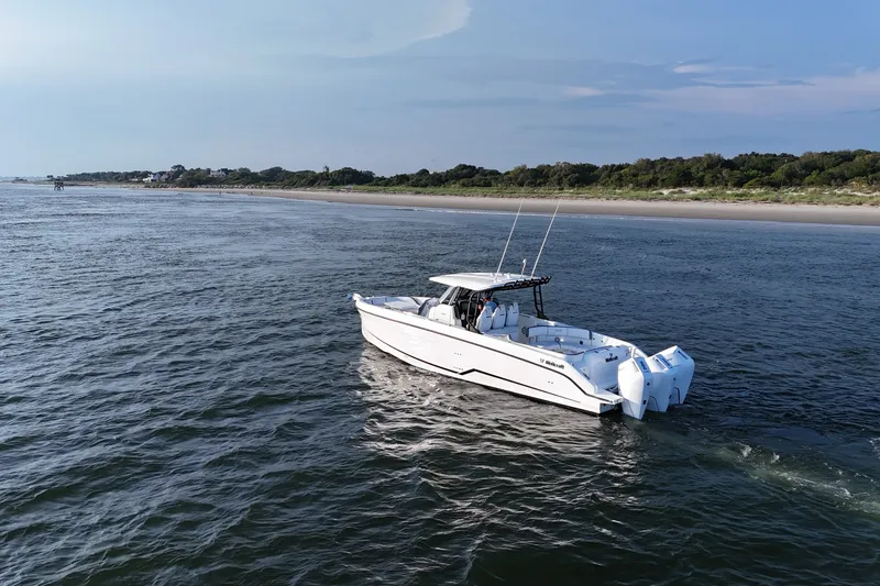 The Image of 2026 Wellcraft 38 T-Top boat cruising near a scenic coastline. - 0