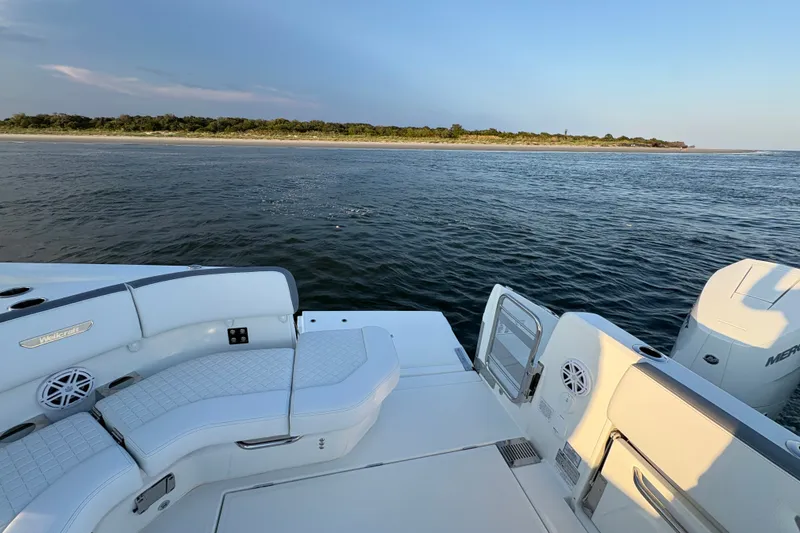 Slide: The Image of 2026 Wellcraft 38 T-Top boat on water, featuring sleek seating and scenic shoreline view. - 14