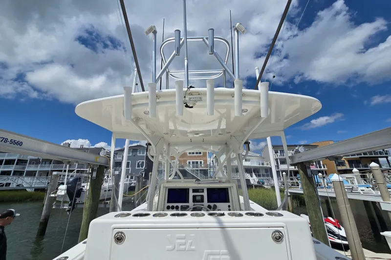 Slide: The Image of 2006 SeaVee 340B boat docked, showcasing helm and rod holders under a blue sky. - 27