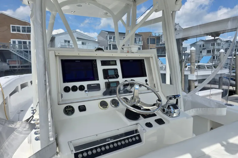 Slide: The Image of 2006 SeaVee 340B boat helm with modern navigation equipment and controls, docked near waterfront homes. - 15