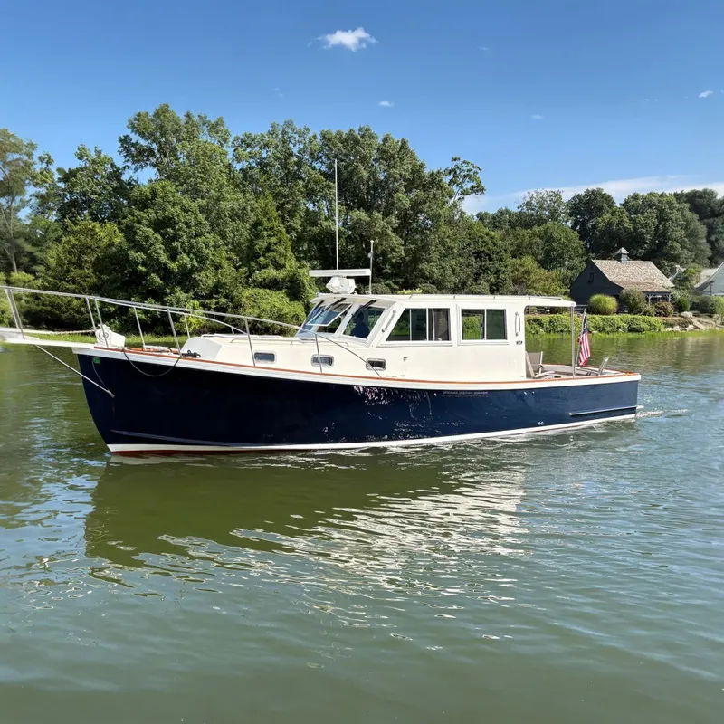 The Image of 1996 Wilbur 34 Weekender boat on calm water, surrounded by lush greenery. - 0