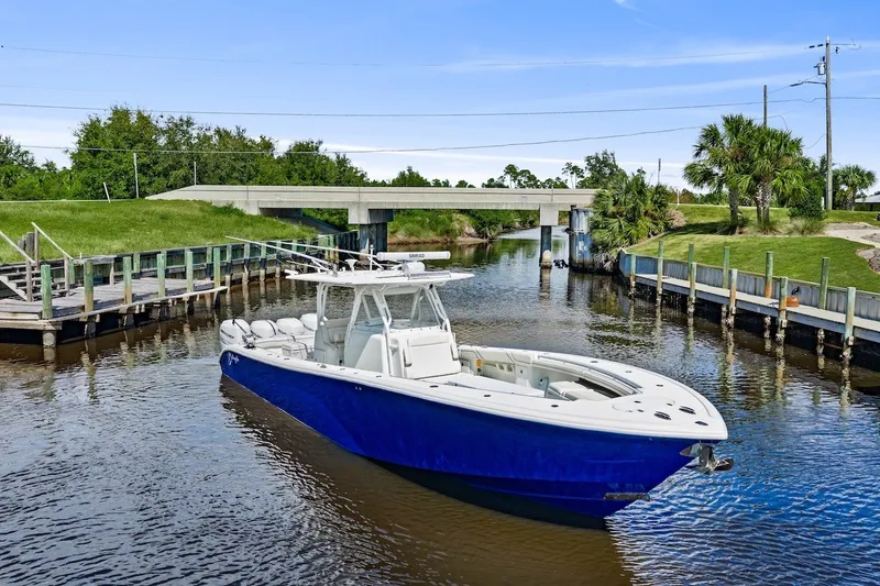 Slide: The Image of 2013 Yellowfin 39 Offshore boat on a calm waterway, surrounded by lush greenery. - 1
