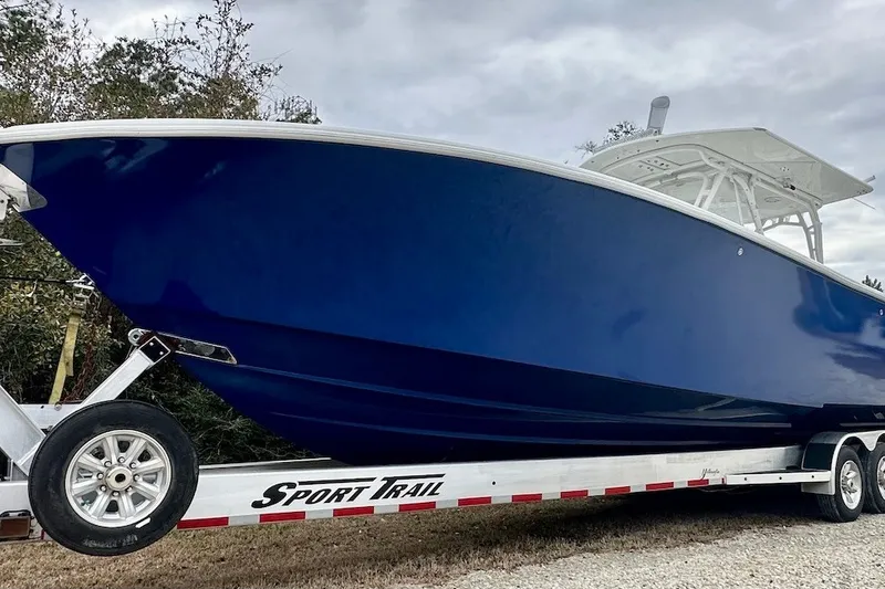 Slide: The Image of 2013 Yellowfin 39 Offshore boat on Sport Trail trailer, blue hull, parked outdoors. - 54
